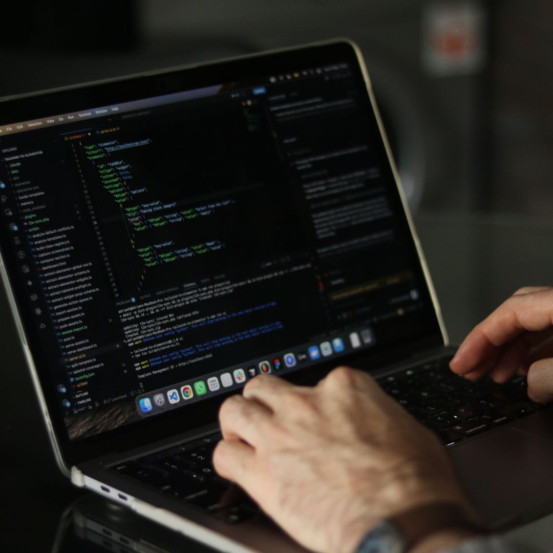Close-up of hands typing code on a laptop keyboard