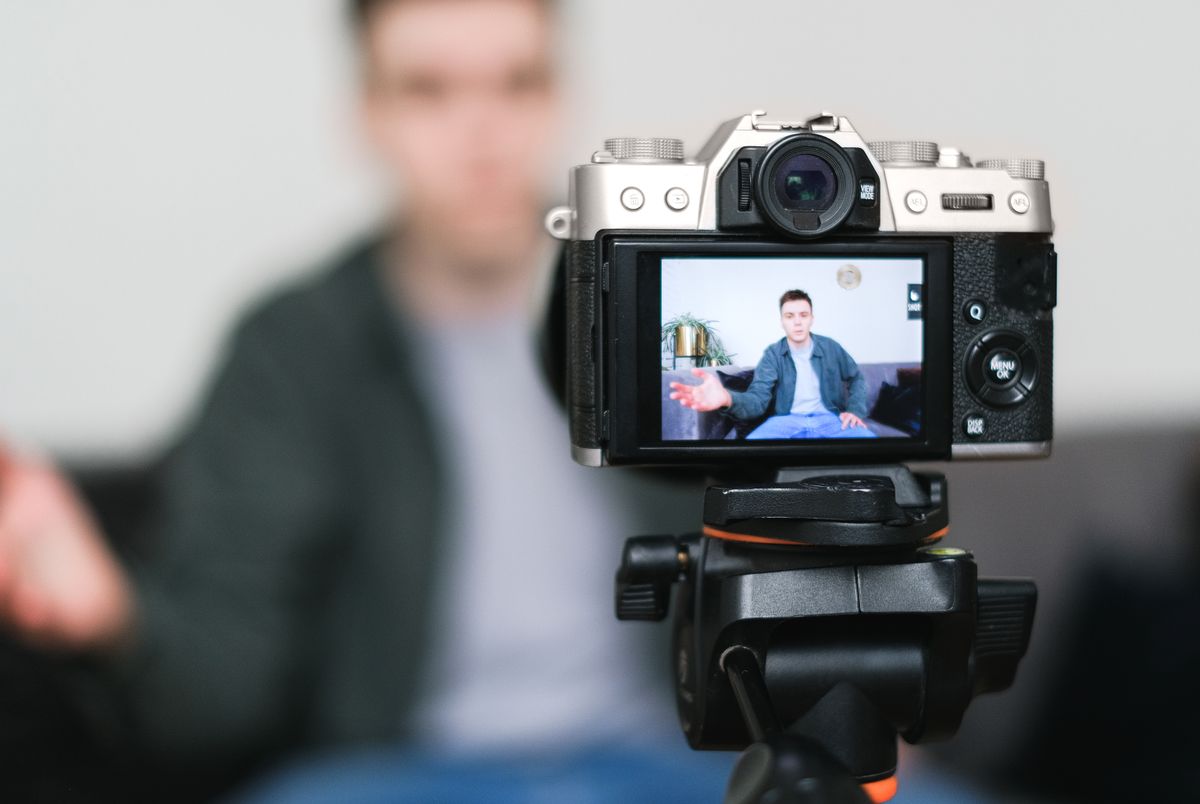 Man recording a vlog indoors using a mirrorless camera on a tripod