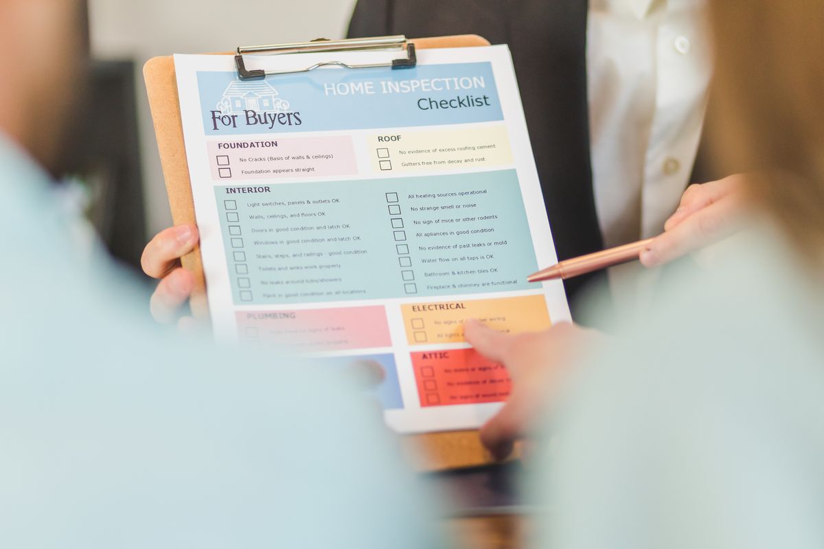 Hands holding a home inspection checklist clipboard during a property walkthrough