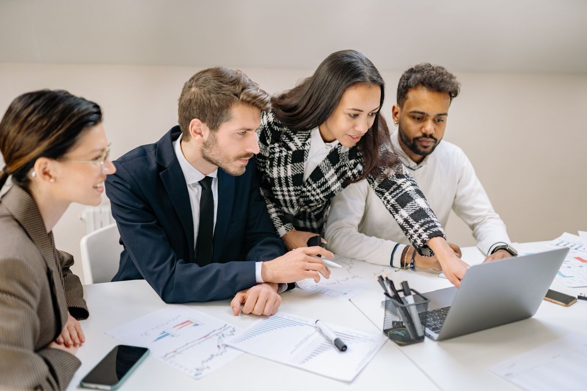Diverse sales team analyzing charts and pipeline data together in an office