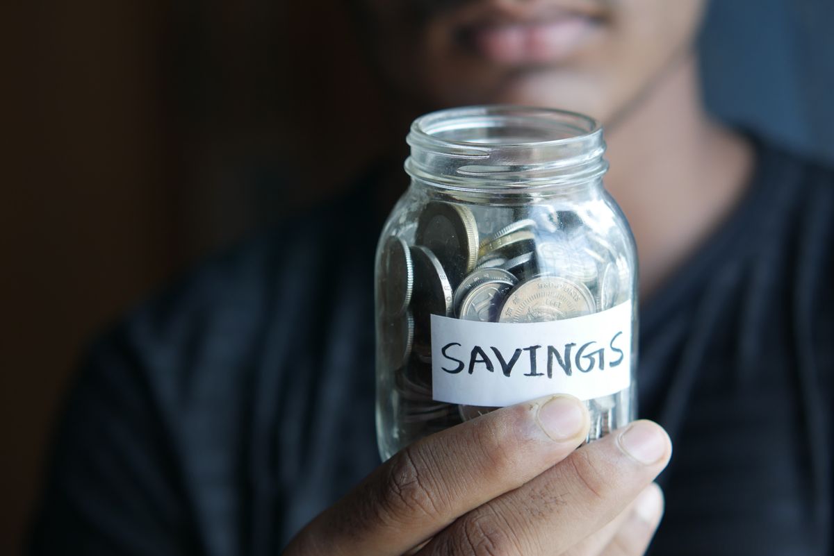 Close-up of a person holding a glass jar full of saved coins