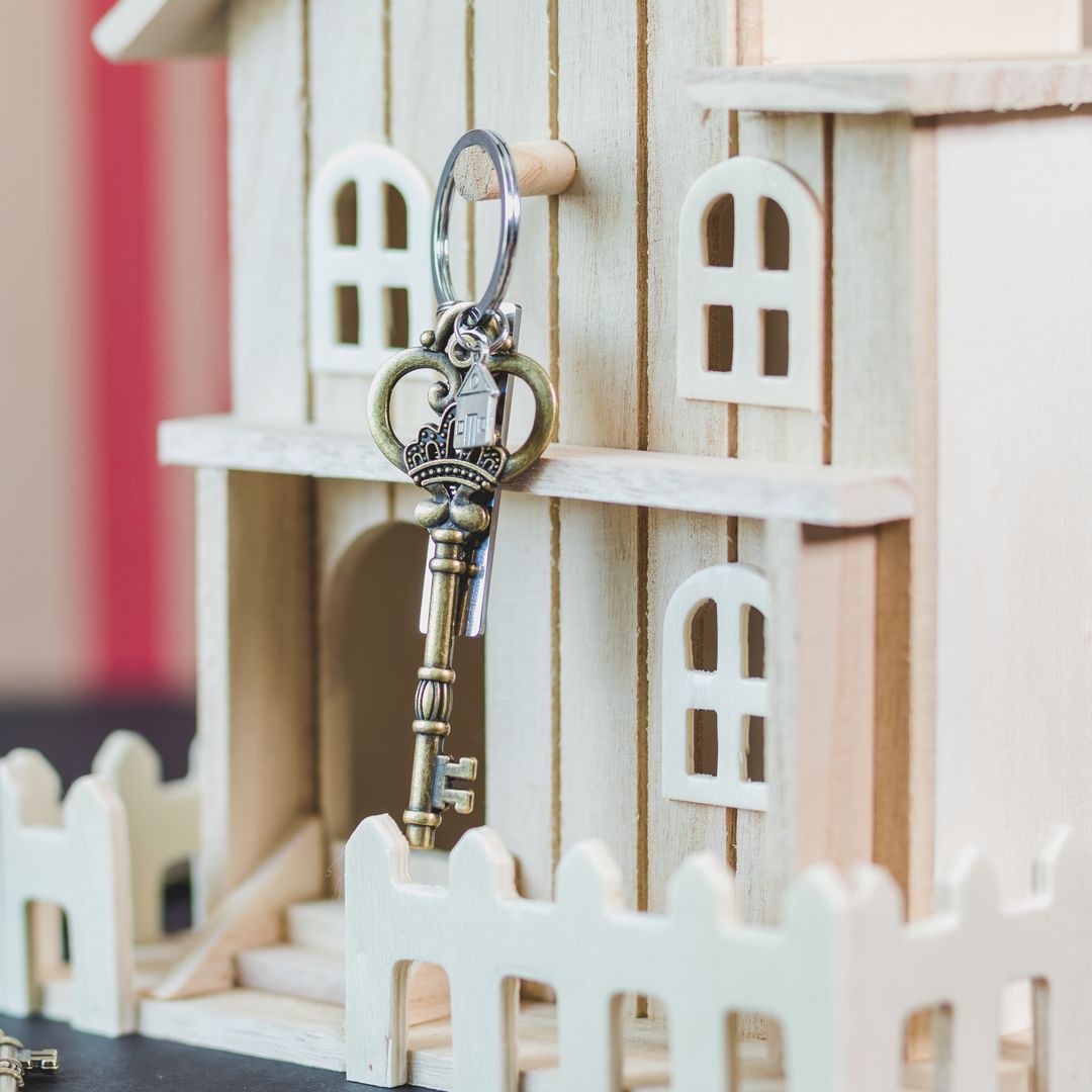 Miniature wooden house with a vintage key beside it