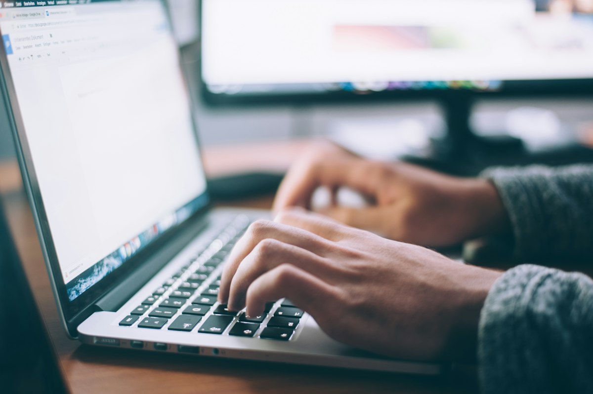 Person typing on a laptop at a bright modern desk