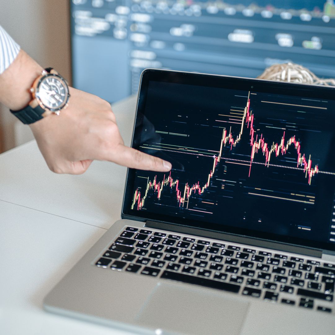 Man pointing at an investment chart on a laptop screen
