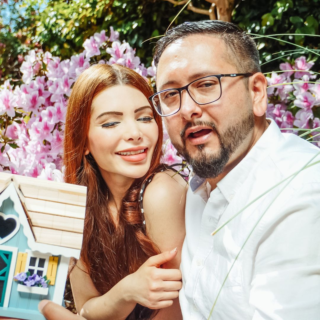 Cheerful couple holding a miniature house