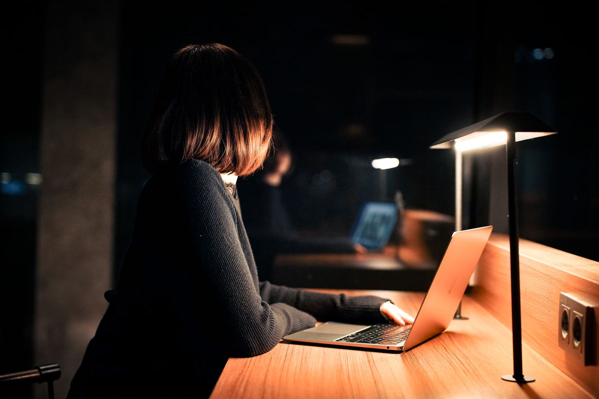 Woman working on her laptop under warm lighting at night