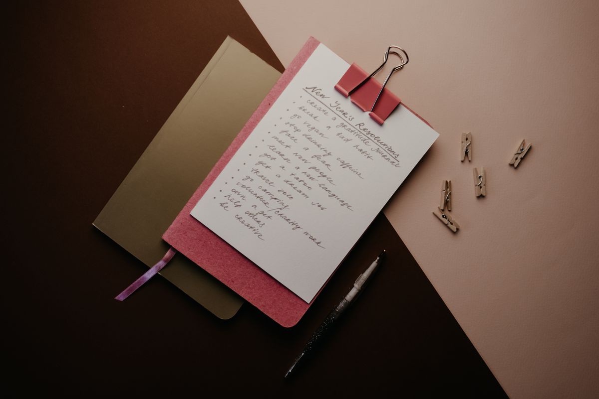 A flat lay of a resolution list on a notepad with warm lighting