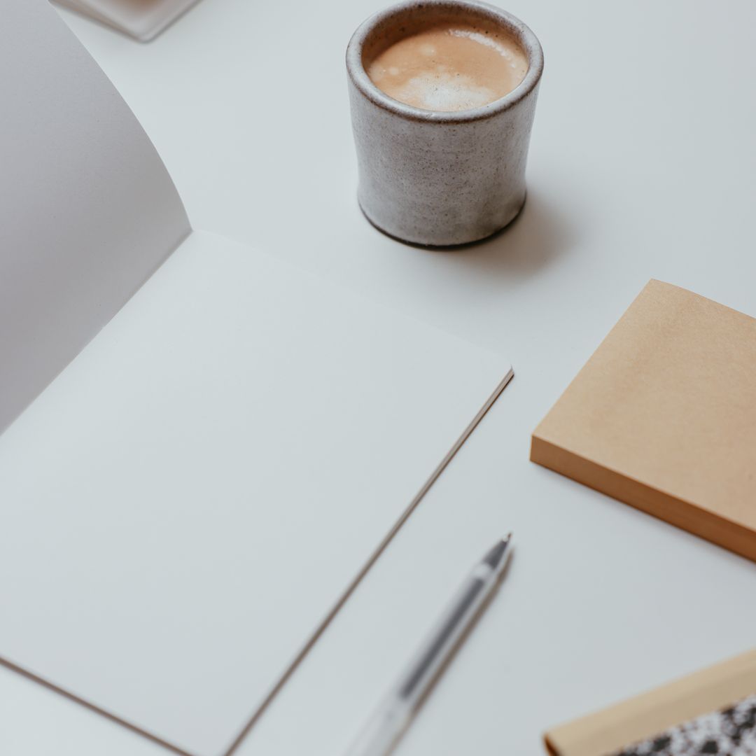 A desk with a notebook, pen, and coffee set up for a writing session