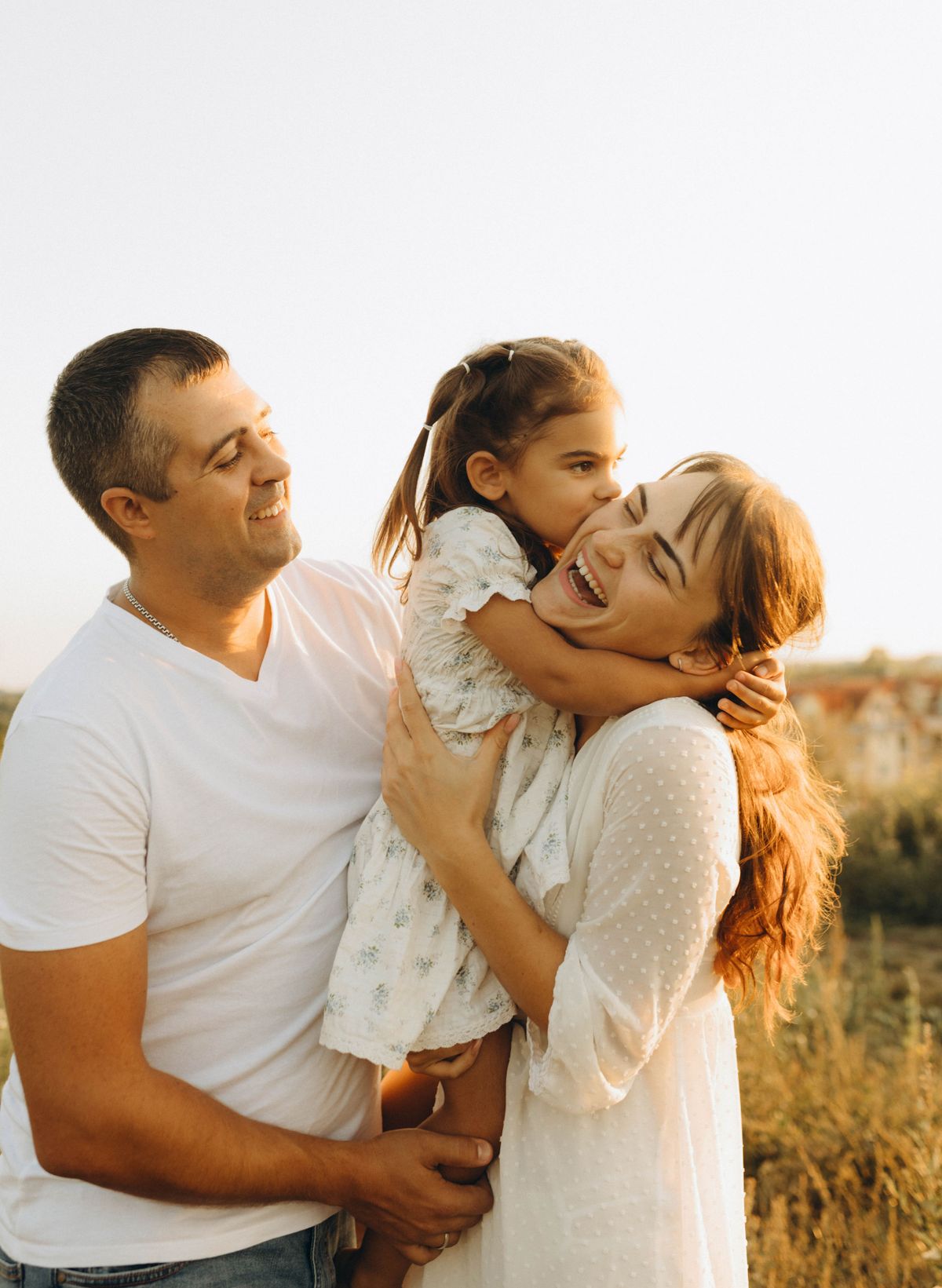 Family embracing outdoors at golden-hour sunset in an open field