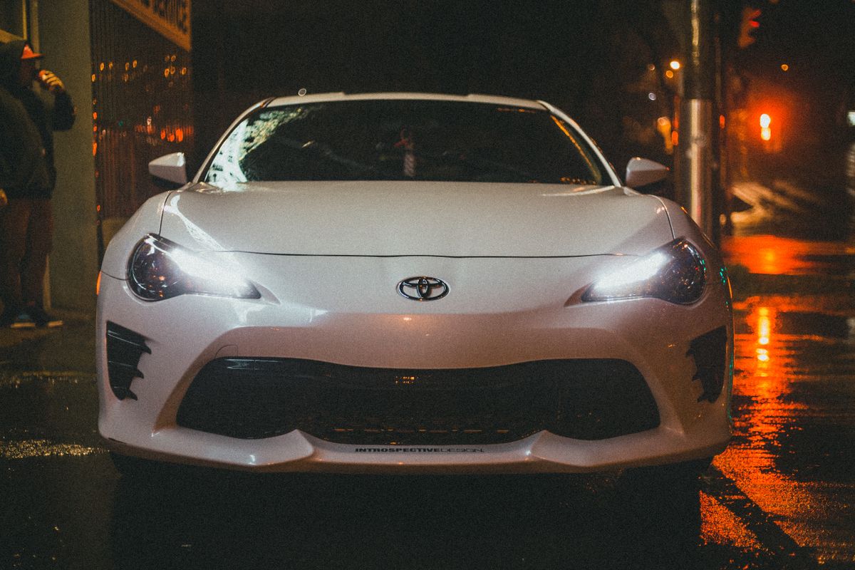 A white car parked on a wet street at night in the city