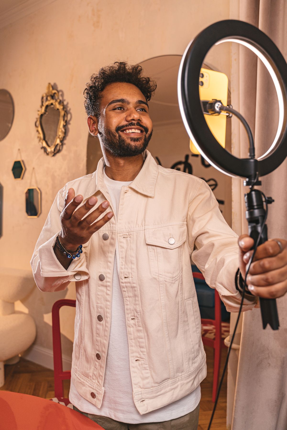A creator filming a product video on a smartphone with a ring light in a cozy room