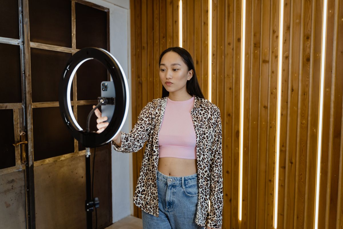 A woman influencer filming a vlog on her smartphone with a ring light in a stylish room