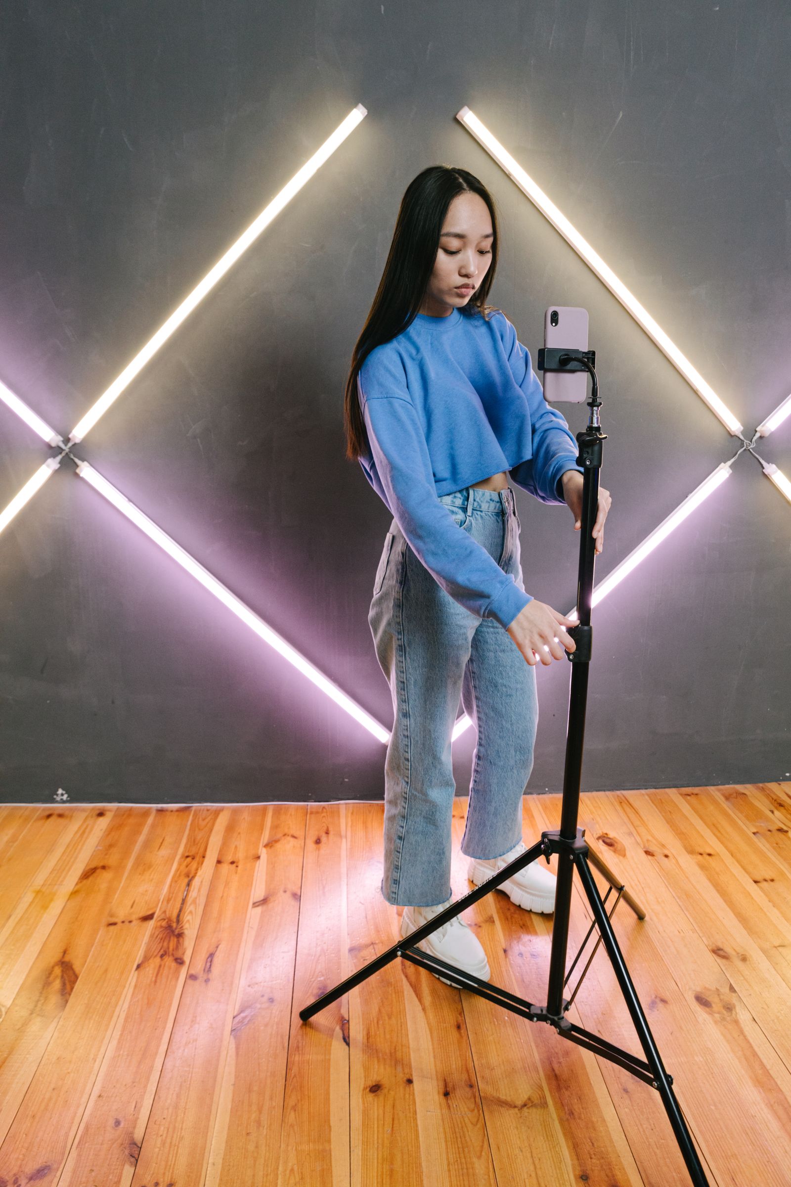 A content creator adjusting a smartphone on a tripod in a studio